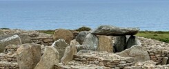 A Neolithic dolmen at Ménez Drégan, Brittany: a large flat capstone resting on upright support stones, set on a hillside of stacked stone walls.